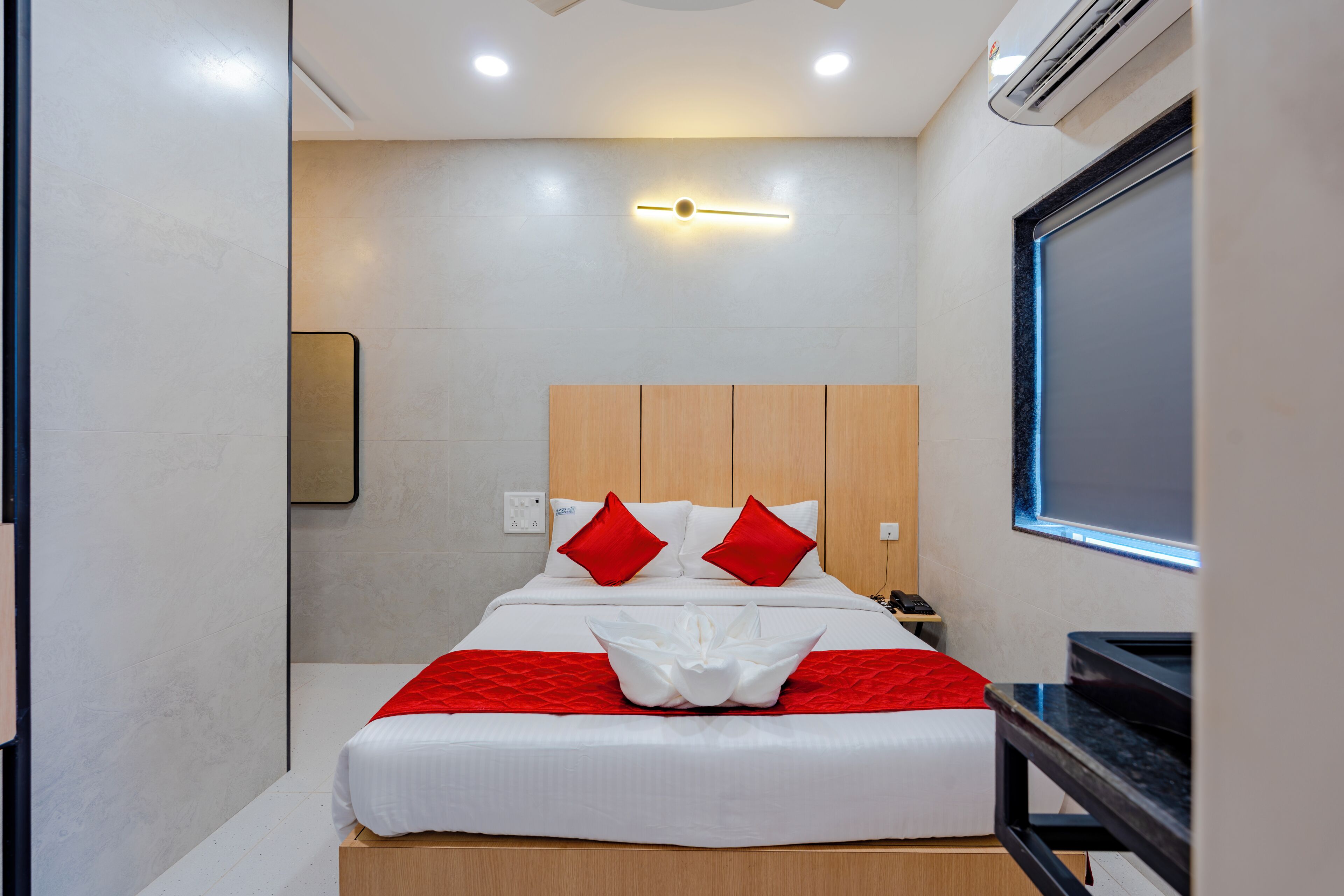 A hotel room with a bed, bedside table, and a window.