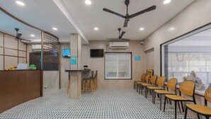 Un hall de hotel con mostrador de recepción, zona de estar y una pantalla de televisión.