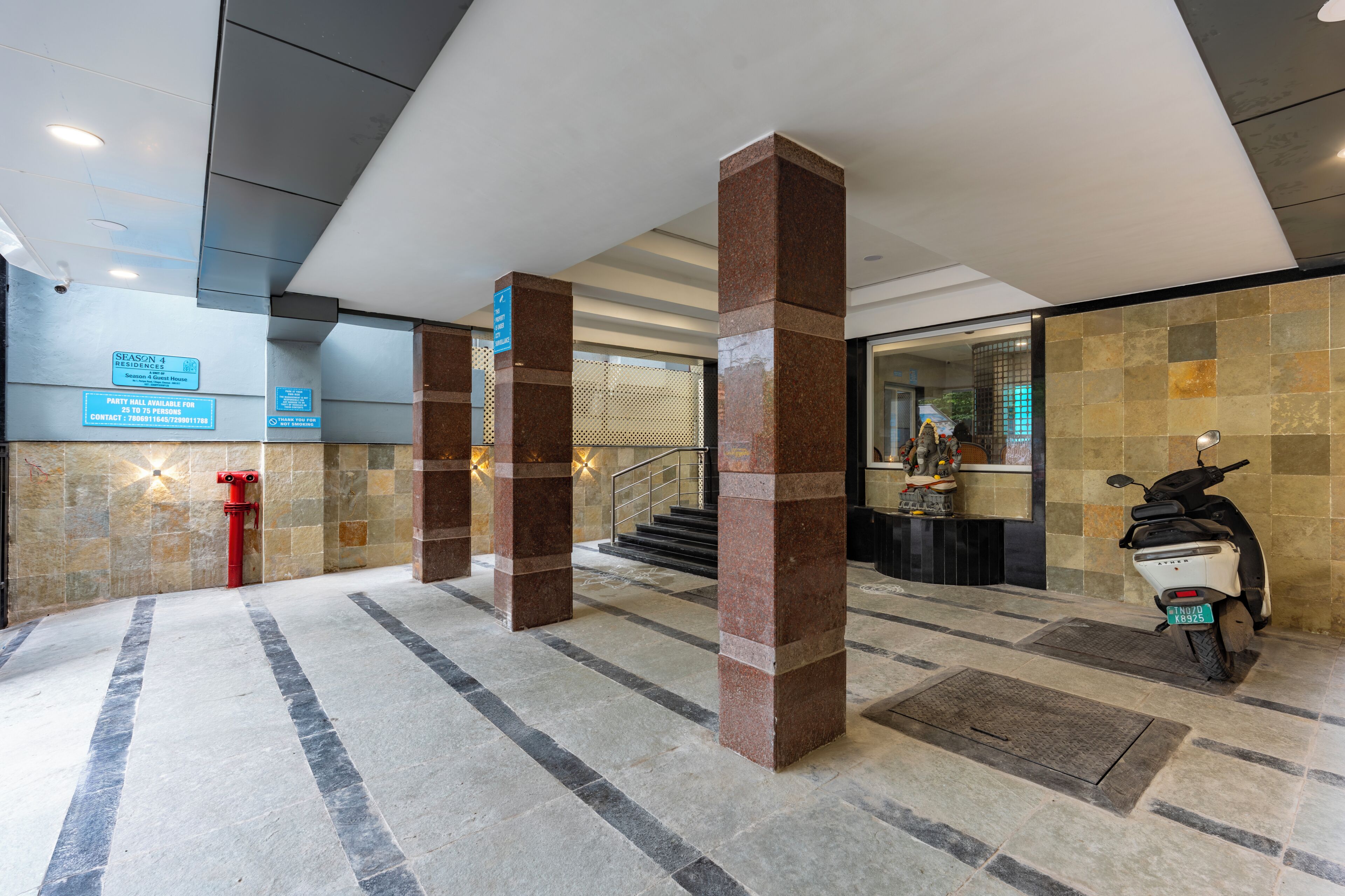 A hotel lobby with a reception desk, a staircase, and a scooter parked by the wall.