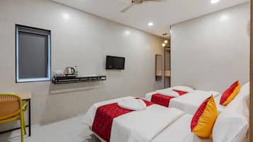 A hotel room with two beds, a TV, a desk, and a chair.