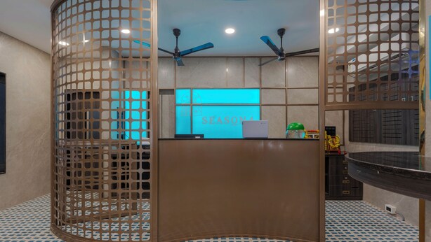 Una zona de recepción con diseño moderno, que presenta un mostrador curvo, un letrero iluminado en azul y ventiladores de techo.