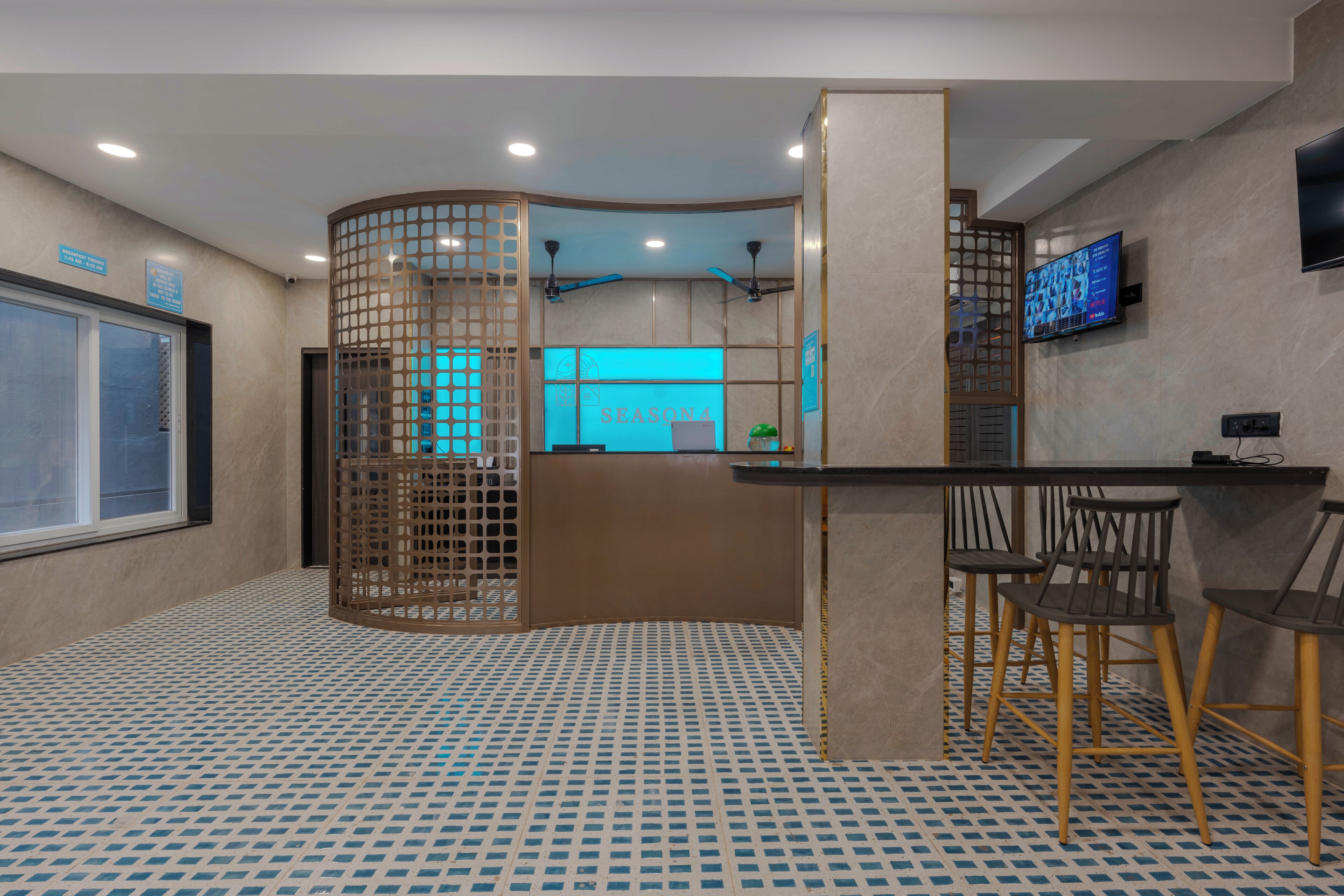 Una hall d'albergo con una reception, uno schermo televisivo e un'area salotto con poltrone.