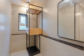 Een badkamer met douchecabine, een raam en een spiegel.