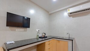 Una cocina compacta con televisión integrada, un lavamanos y una cafetera.