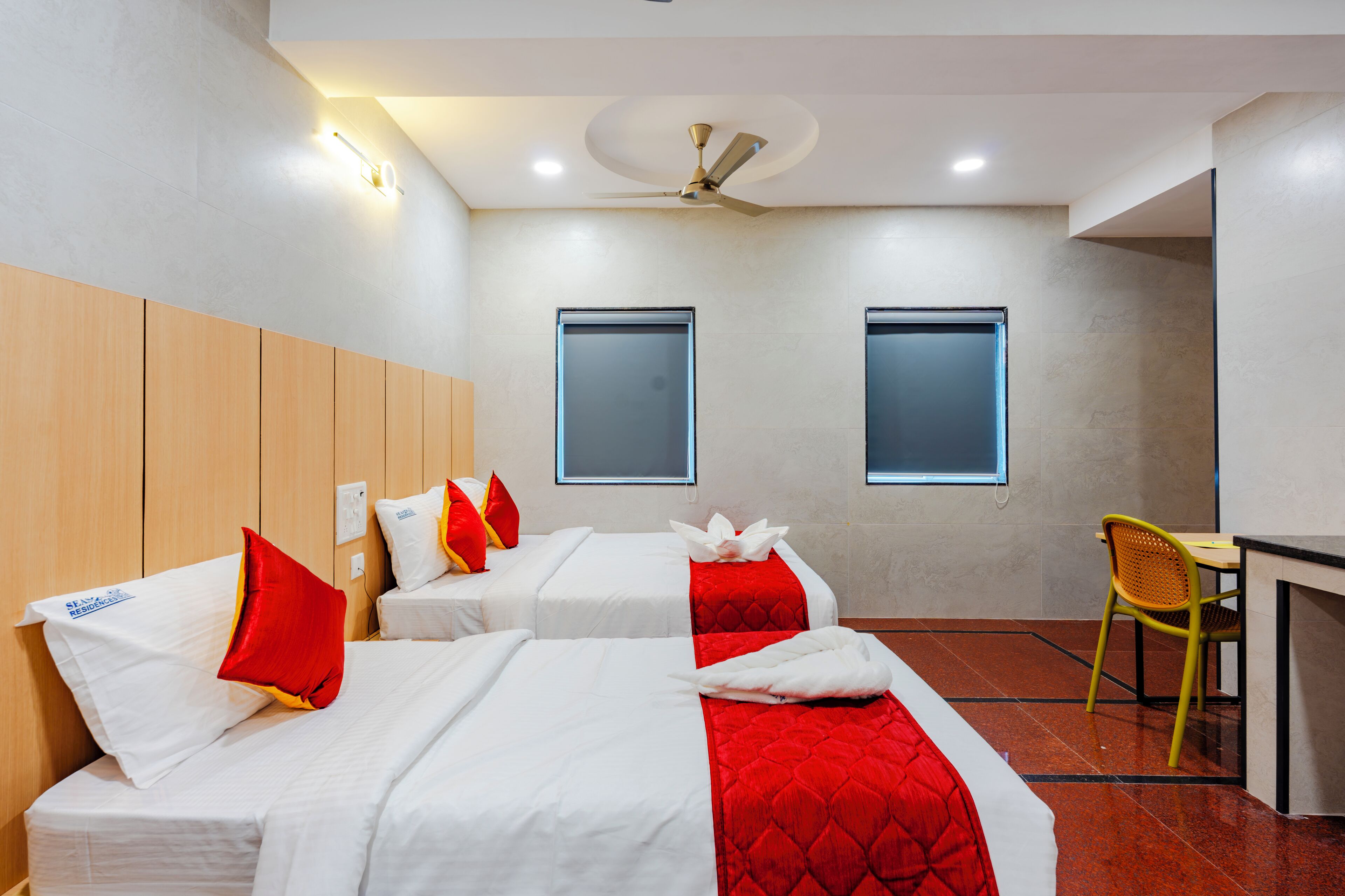 A hotel room with two beds, a desk, and a chair.