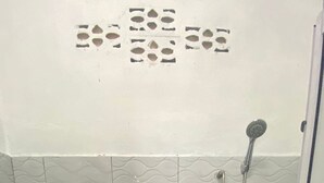A small, enclosed bathroom with a toilet, a shower, and a tiled wall. - Hotel O D Longan Cottage (Sungai Petani)