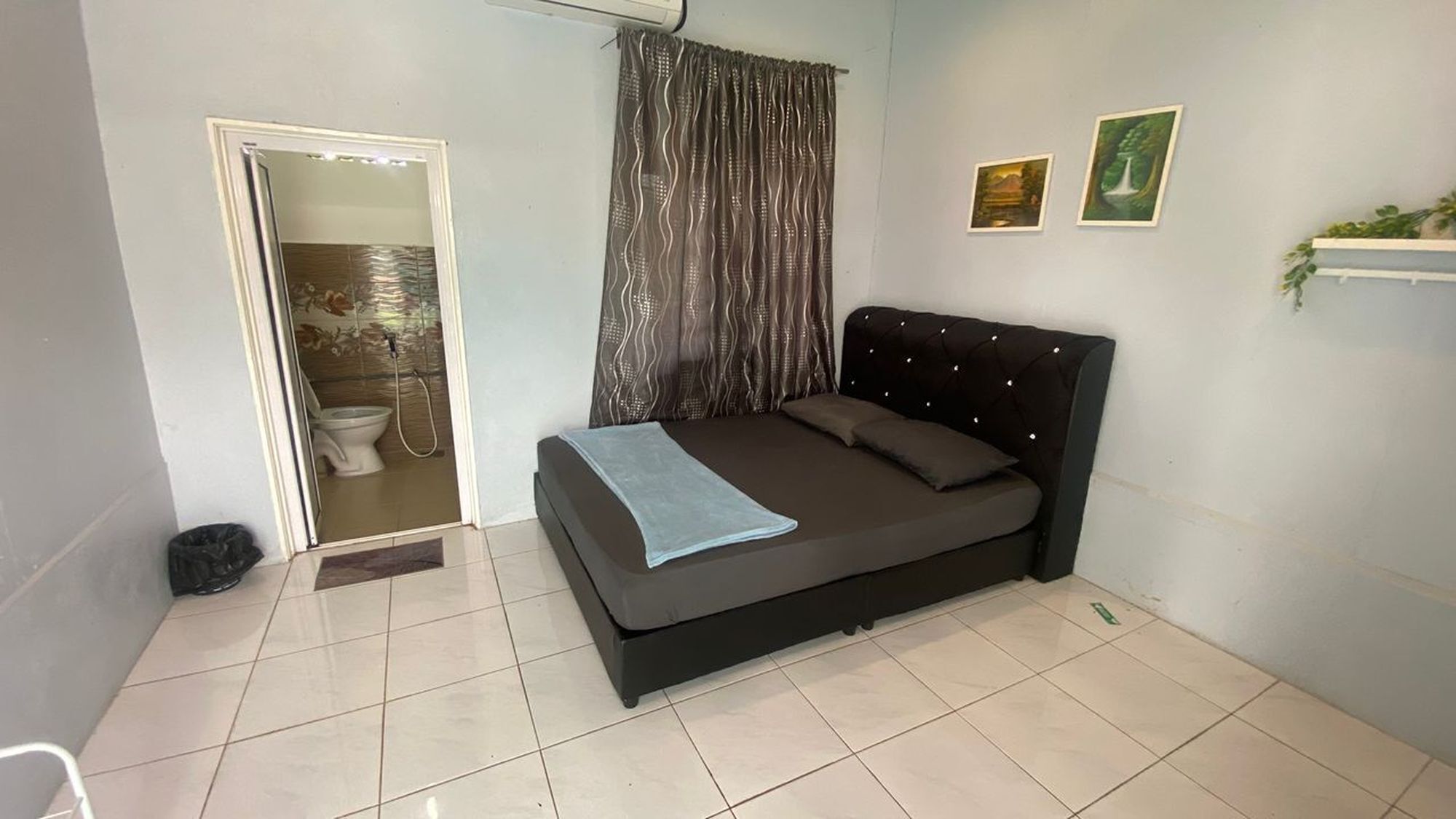 Un dormitorio con cama, zona de ducha y dos cuadros en la pared.