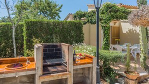 An outdoor barbecue area with a grill, a table with chairs, and a lamp post. - Countryside Villa in Pollensa (Pollença)