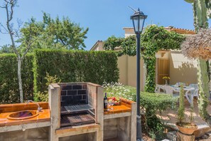 An outdoor barbecue area with a grill, a table with chairs, and a lamp post. - Countryside Villa in Pollensa (Pollença)
