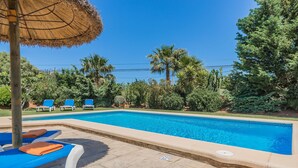 A swimming pool with lounge chairs and a thatched umbrella. - Countryside Villa in Pollensa (Pollença)