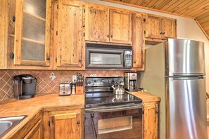 Eine Küche mit Holzschränken, einem Edelstahl-Kühlschrank, einer Mikrowelle, einem Herd und einer Kaffeemaschine.