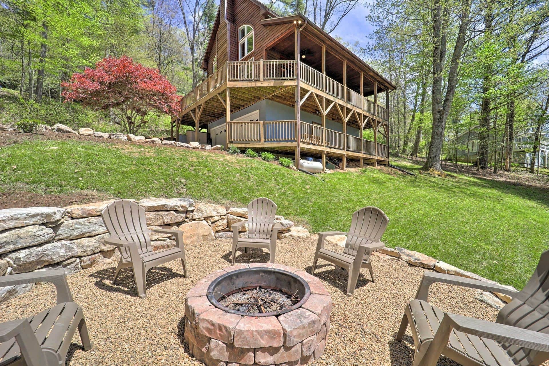 A cabin with a deck, surrounded by a fire pit and outdoor seating.