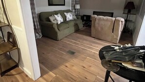 Un salón con un sofá, una silla, una mesa con objetos y un ventilador de techo.