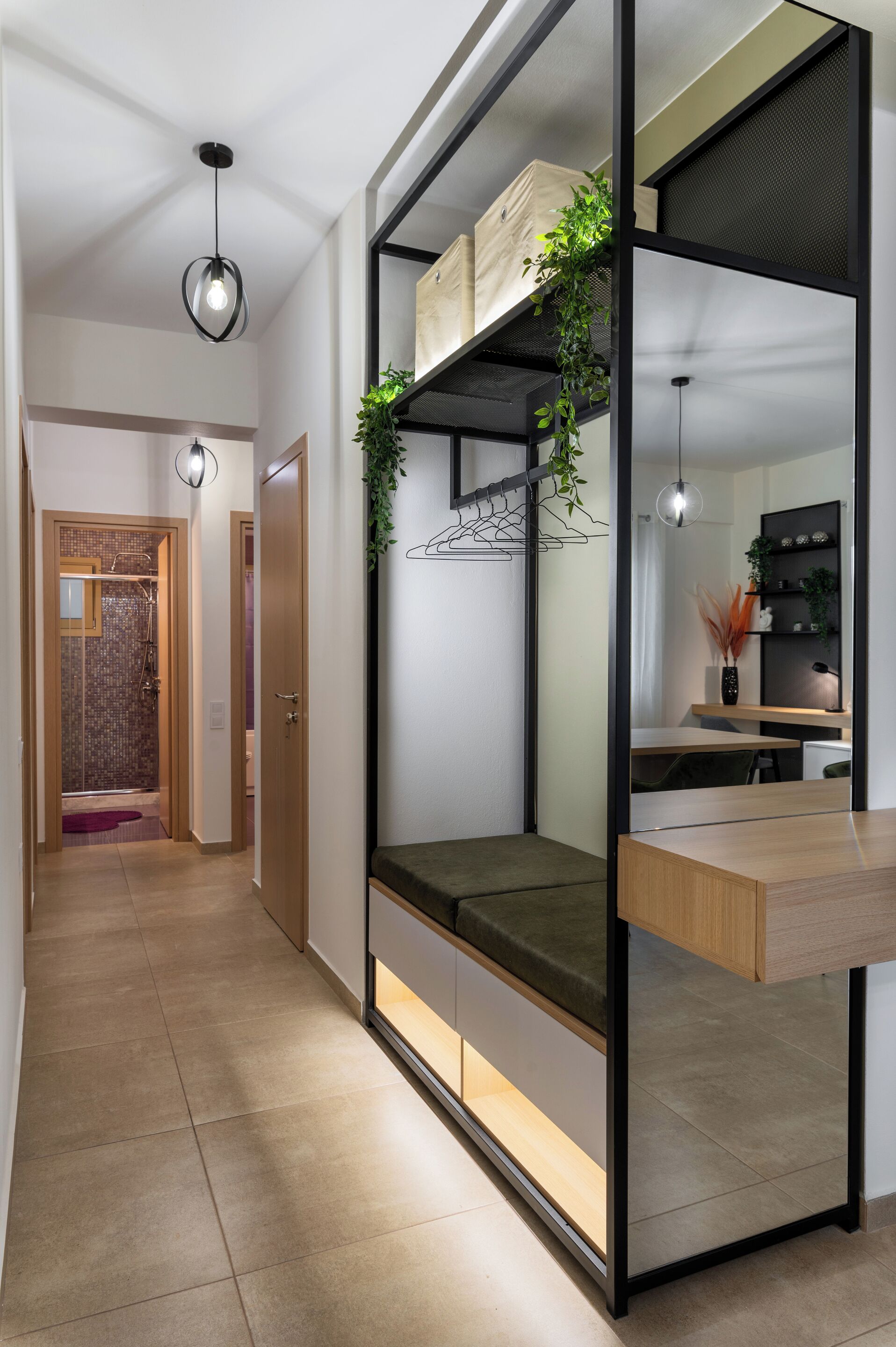 A modern interior with a built-in bench, a hanging plant, and a kitchen area visible through a glass partition.