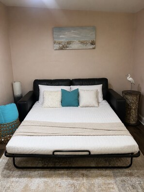A bedroom with a bed, a nightstand, a lamp, a decorative bird, and a painting on the wall. - Perfect 1-bedroom cottage with AC in charming Bay St. Louis, 1 mile to beach (Bay St. Louis)