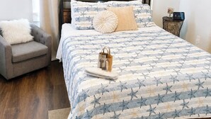 Ein Schlafzimmer mit einem Bett, einem Sessel, einem Nachttisch und einem Deckenventilator.