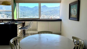 A modern kitchen with a dining area, large windows with a city and mountain view, and a framed artwork on the wall. - Apartment in Leblon, Rio de Janeiro!
Best neighborhood, 2 blocks from the beach. (Rio de Janeiro)