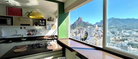 A modern kitchen with a view of a cityscape and mountains.
