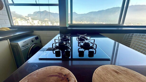 A kitchen with a gas stove, a washing machine, and a view of mountains through large windows. - Apartment in Leblon, Rio de Janeiro!
Best neighborhood, 2 blocks from the beach. (Rio de Janeiro)