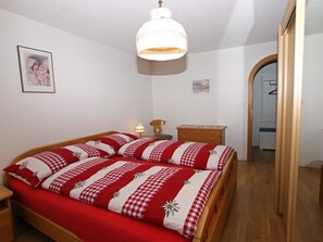 Ein Schlafzimmer mit einem Bett, einem Nachttisch, einer Lampe und einer Tür zu einem anderen Raum.