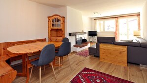 En kompakt opholdsstue med spisebord, stole, sofa, fjernsyn og pejs.