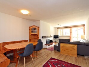 Ein gemütlicher, kompakter Wohnbereich mit Esstisch, Stühlen, einer Couch, einem Fernseher und einem Kamin.