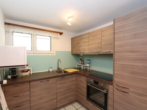 Eine kleine Küche mit Holzausstattung, einer Edelstahl-Spüle und einem eingebauten Backofen.