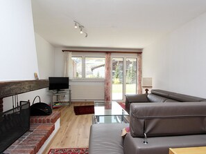 Ein Wohnzimmer mit Sofa, Fernseher und Kamin.