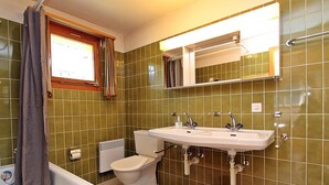 Une salle de bain équipée d’une baignoire, de toilettes, d’un bidet et d’un lavabo.