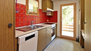 Une cuisine de taille réduite, équipée d’un évier, d’une cuisinière et de meubles de rangement en bois.