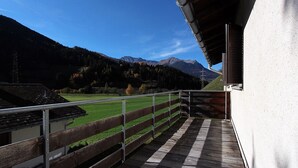 Un balcon donnant sur un champ verdoyant et des montagnes.