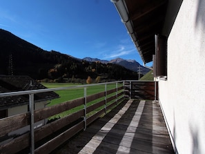 Ein Balkon mit Blick auf ein grünes Feld und Berge.