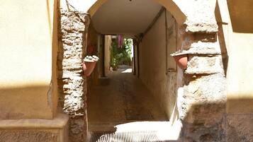 A narrow stone corridor with a metal grate at the bottom, flanked by walls with terracotta pots.