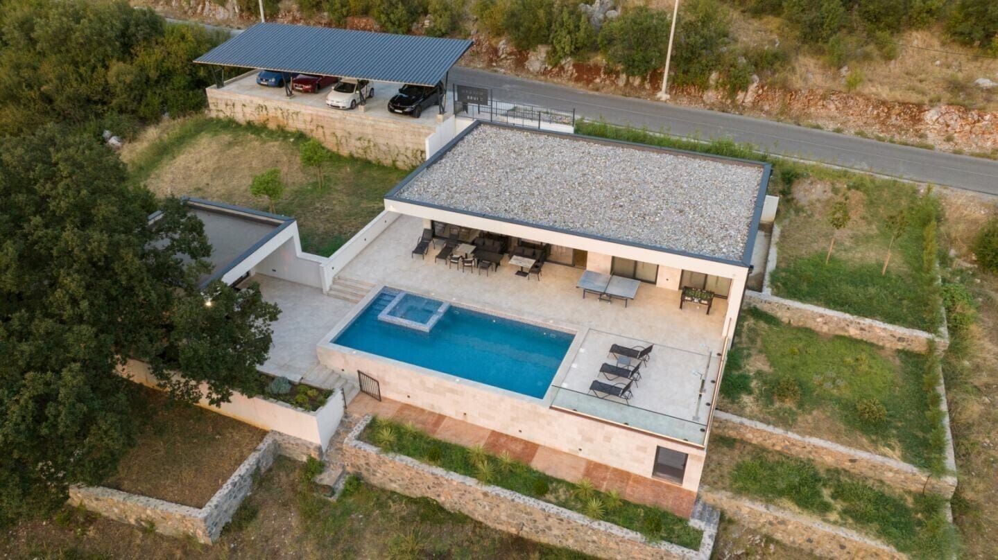 A modern house with a swimming pool, outdoor seating, and a covered car parking area.