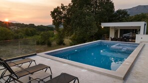 Una piscina rectangular con agua cristalina azul, rodeada por un solárium con baldosas.