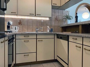 Eine Küche mit Backofen, Kaffeemaschine, Spüle und einem Topf mit Pflanze.