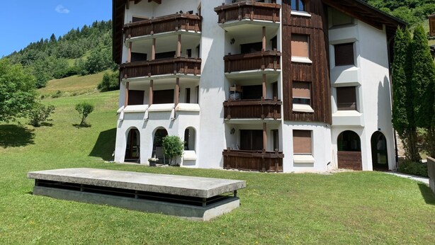 A multi-story building with balconies, set in a mountainous area with a grassy foreground. - Cadras 10 Appartement/Fewo, Bad, WC, 2 Schlafräume 3 Zimmerwohnung - 4 Betten by Interhome (Tinizong)