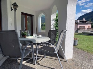 Eine Terrasse im Freien mit Tisch, Stühlen, einem Blumentopf und Blick auf einen Berg.