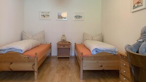 A room with two wooden beds, a nightstand, a lamp, and three framed pictures on the wall. - Cadras 10 Appartement/Fewo, Bad, WC, 2 Schlafräume 3 Zimmerwohnung - 4 Betten by Interhome (Tinizong)