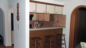 A kitchen with wooden cabinets, a countertop, and three stools. - Cadras 10 Appartement/Fewo, Bad, WC, 2 Schlafräume 3 Zimmerwohnung - 4 Betten by Interhome (Tinizong)