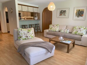 A modern living room with a sofa, a coffee table, and a kitchen area in the background. - Cadras 10 Appartement/Fewo, Bad, WC, 2 Schlafräume 3 Zimmerwohnung - 4 Betten by Interhome (Tinizong)