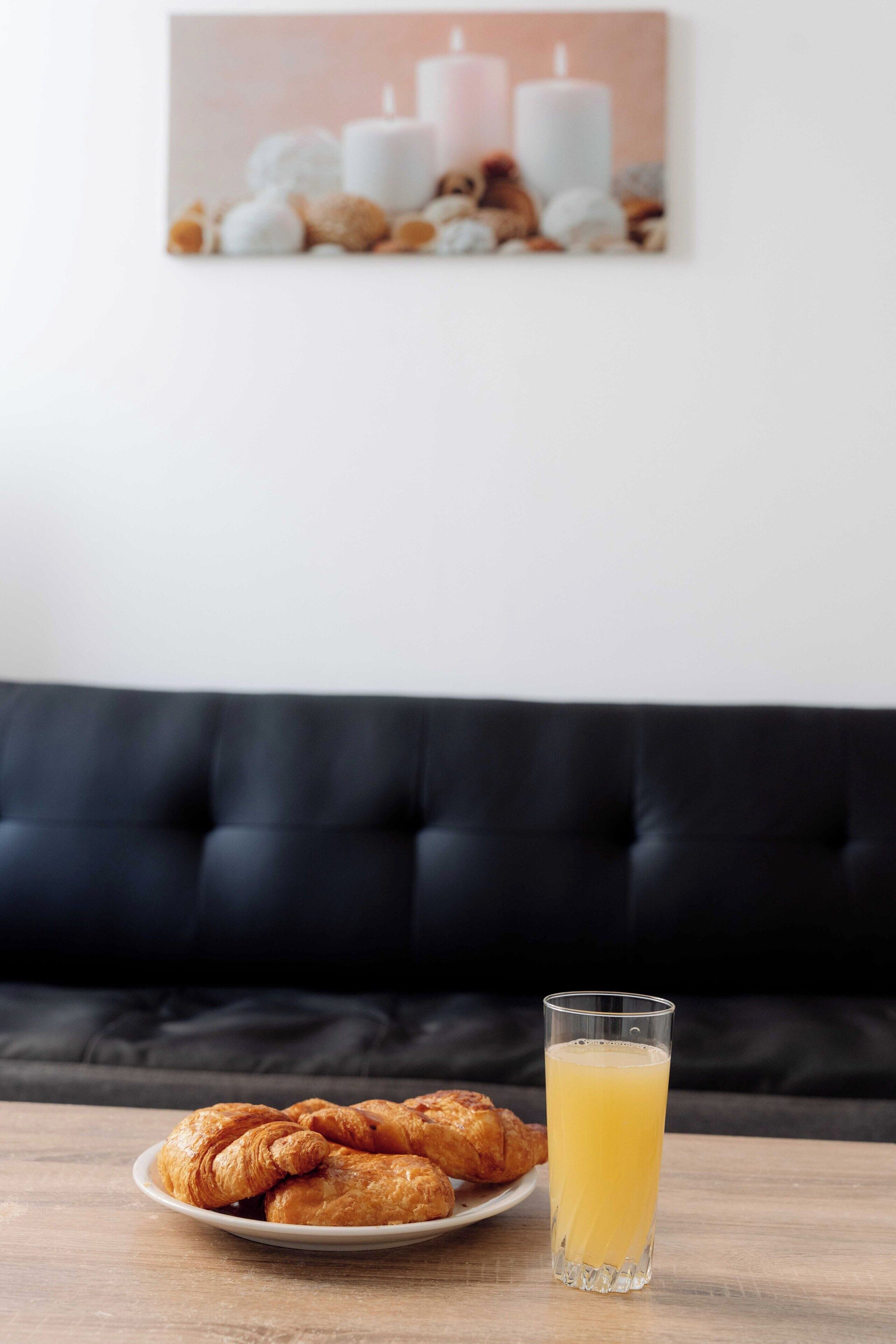 A plate of croissants and a glass of orange juice on a wooden table.