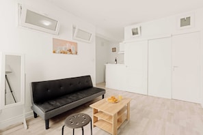 A modern living room with a black sofa, a wooden coffee table, and a small stool. There is a white wardrobe and a white cabinet with a wine bottle and glasses on top. - Cozy Appartement 1br/2p - Vieux Lyon (Lyon)