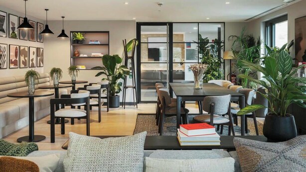 A modern living room with a sofa, coffee table, and dining area. - Student Only Clay Wembley (Wembley)