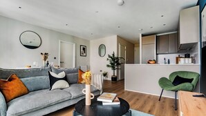 A modern living room with a grey sofa, a coffee table, and a green chair. - Student Only Clay Wembley (Wembley)