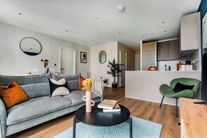 Ein modernes Wohnzimmer mit einem grauen Sofa, einem Couchtisch und einem grünen Sessel.