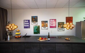 Una cocina moderna con una isla central, diversos electrodomésticos y una pared decorada con carteles de colores.
