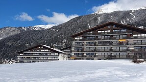 Un hôtel à plusieurs étages, doté de balcons, qui se dresse sur fond de montagnes enneigées.