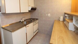 Une cuisine de taille réduite, équipée d’une cuisinière, d’un évier et d’un plan de travail en bois.