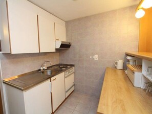 A compact kitchen with a stove, sink, and wooden countertop. - Las Vals B5 Appartement/Fewo, Bad, WC, 2 Schlafräume 3 Zimmerwohnung - 5 Betten by Interhome (Savognin)